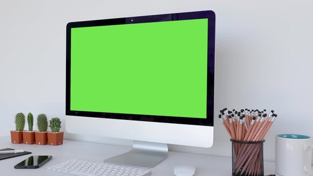 Computer desktop with mock-up green screen white background  in office, Shoulder view.