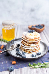 rustic Breakfast pancakes on a dark plate with blueberries and honey
