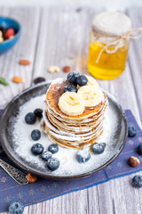 rustic Breakfast pancakes on a dark plate with blueberries and honey