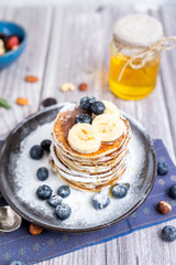 rustic Breakfast pancakes on a dark plate with blueberries and honey