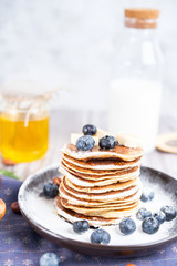 pancakes on a plate with blueberries and milk