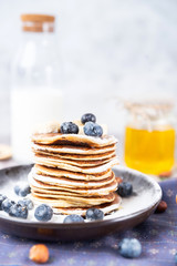 pancakes on a plate with blueberries and milk