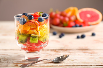 Glass with tasty fruit salad on table