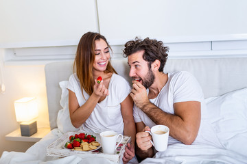 Young married couple in love eating breakfast in their bed. Good morning! Healthy breakfast in bed. Young beautiful love couple is having breakfast in bed.