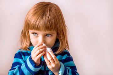 beautiful little girl uses a nasal spray for allergies or illness, plain background, the concept of colds and viral seasonal diseases