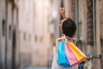 Young girl with shopping bags on narrow street in Europe.