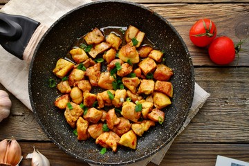 Chicken meat in a pan. Sliced ​​ chicken breast fried in a pan, wooden background.