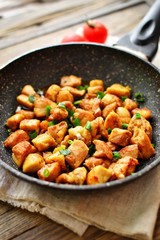 Chicken meat in a pan. Sliced ​​ chicken breast fried in a pan, wooden background.