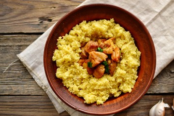 Couscous in a clay plate on a wooden background with linen textiles. Couscous with meat. Photo of food.