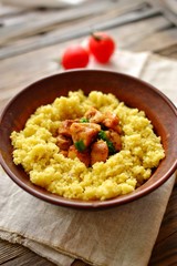 Couscous in a clay plate on a wooden background with linen textiles. Couscous with meat. Photo of food.
