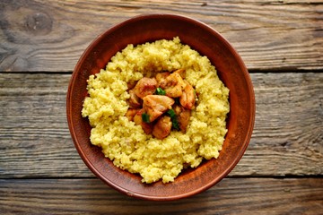 Couscous in a clay plate on a wooden background with linen textiles. Couscous with meat. Photo of food.