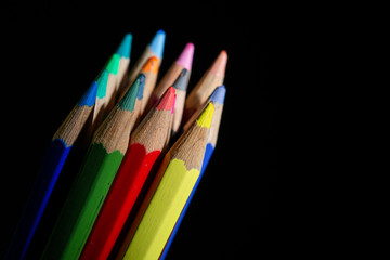 GROUP OF COLORED PENCILS ALIGNED ON BLACK BLACKGROUND