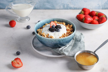Tasty granola with yogurt in bowl on table