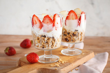 Tasty granola with yogurt in glasses on wooden table