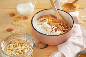 Tasty granola with yogurt in bowl on wooden table