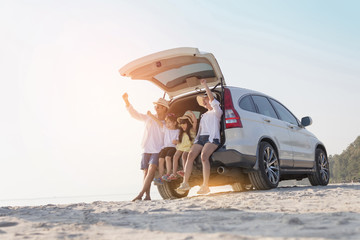 Cheerful parents, children are playing on the sandy beach with happiness in summer.
