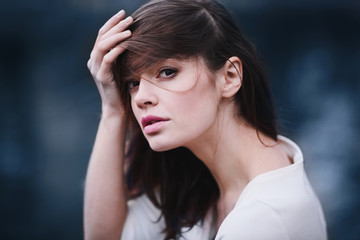 Charming young woman with dark hair and a beautiful neck in autumn park. Deep pensive look.