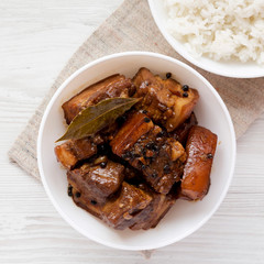 Homemade Filipino Adobo Pork with rice on a white wooden table, top view. Flat lay, overhead, from above. Close-up.