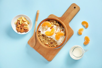 Fototapeta premium Tasty granola with yogurt in bowl on color background