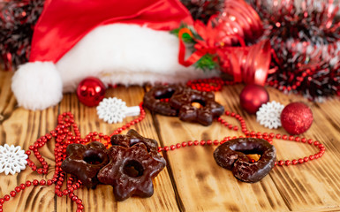 Christmas and New Year decorations on a wooden background. Gingerbread cookies, Santa Claus hat and other Xmas accessories on a table. 