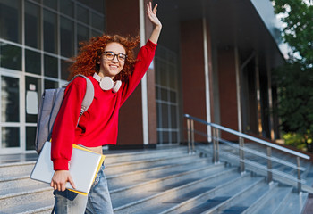 Happy red haired student leaving university