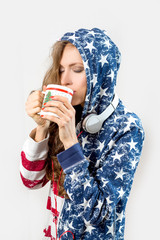 Young woman in amercan flag colors drinking tea or coffee with headphones  isolated over white