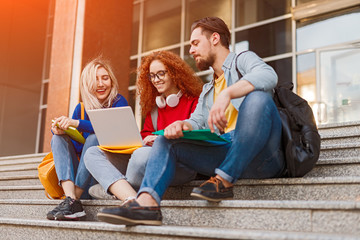 Group of friends using laptop outside university