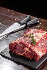 Raw meat. Beef tenderloin, neck lies on a black board, next to a knife and knife sharpener. closeup. background image. copy space