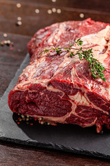 Raw meat. Beef tenderloin, neck lies on a black board, next to a knife and knife sharpener. closeup. background image. copy space
