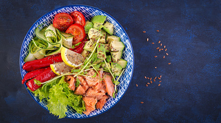 Healthy grilled salmon, avocado, tomato, cucumber, paprika and chia seeds. Balanced lunch in blue bowl. Buddha bowl. Top view, flat lay