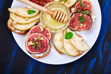 Bruschetta and Crostini with pear, ricotta cheese, honey, figs, nuts and herbs. Breakfast toasts or snack sandwiches. Antipasto. Italian food. Top view. Copy space.