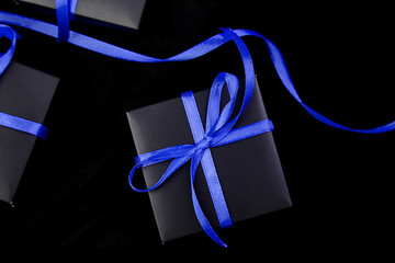 Luxury black gift boxes with blue ribbon on shine black background. Christmas, birthday party presents. Father Day. Flat lay. Copy space. Top view.