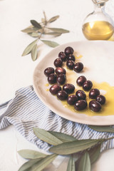 Mediterranean olives in natural virgin olive oil on white ceramic plate and olive tree branch  on the white soft background