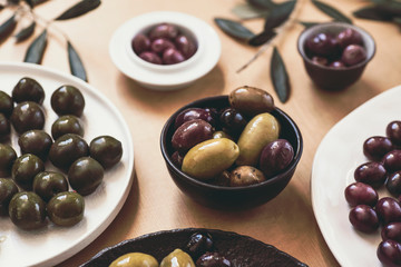 Various kinds of  Mediterranean olives on the warm orange background (Neapolitan sweets, Kalamata and  baked olives)