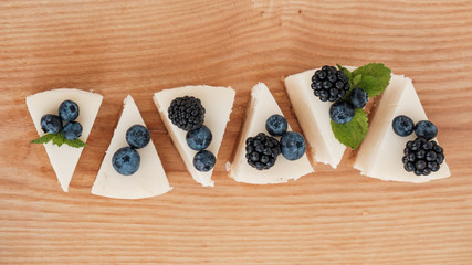 sliced cheesecake in portions with blackberries and blueberries on a wooden board. home food concept. home food concept.