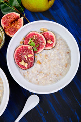 A bowl of porridge with figs slices and walnuts  on dark blue background. Flat lay. Copy space. Top view. Healthy breakfast.