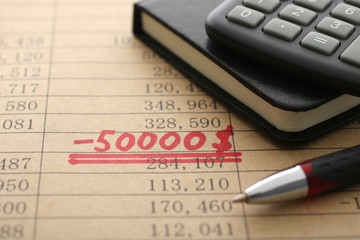 数字の統計と計算機と筆記用具と赤字