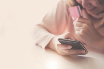 Close up hand of woman holding credit card and using smartphont at home. Online shopping concept