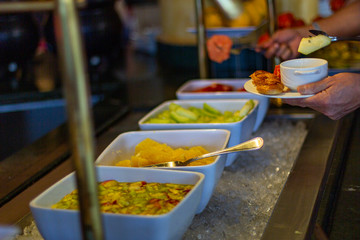 People choose fruits from the hotel breakfast buffet.
