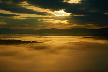 Fototapeta na wymiar The dawn sun illuminates the fog in the mountains.