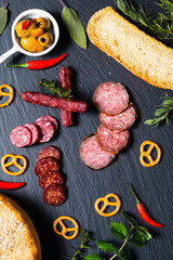 Food party background 3kind of meat Saucisson french salami, olive, prezels and homemade bread on black slate stone