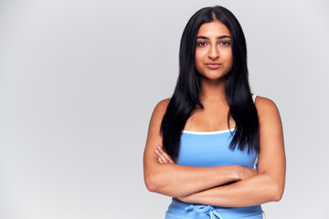 Studio Portrait Of Woman With Serious Expression And Folded Arms Looking At Camera