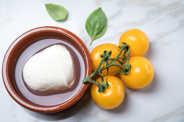 Gelbe Tomaten mit Mozzarella und Basilikum auf Marmor Hintergrund 