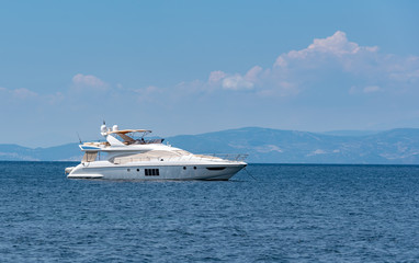 Fototapeta na wymiar Luxury white yacht on horizon at the sea with island sillhouette at background
