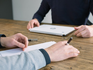 Two business people have meeting round a wooden table at an office.