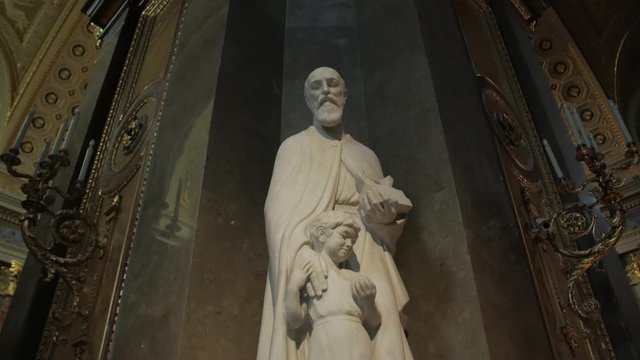 Statue of catholic saint in church with light halo over head Saint Joseph by Pal Patzay in temple St. Stephen's Basilica in Budapest Hungary gimbal smooth camera movement
