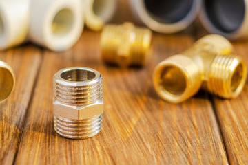 Brass fitting against the background of spare parts for plumbing on vintage boards