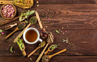 Assortment of dry tea in spoons on a wooden background. Top view with copy space.