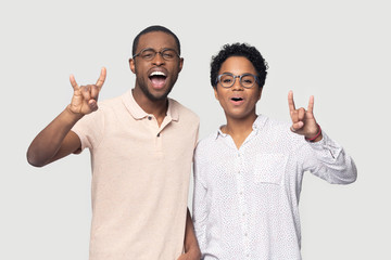 Overjoyed mixed race ethnic married couple showing rock-n-roll gesture.
