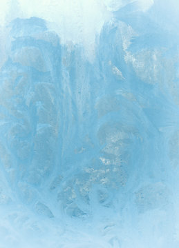 Fantastic fairy-like light blue frost pattern on the window glass (as an abstract winter background), retro toned